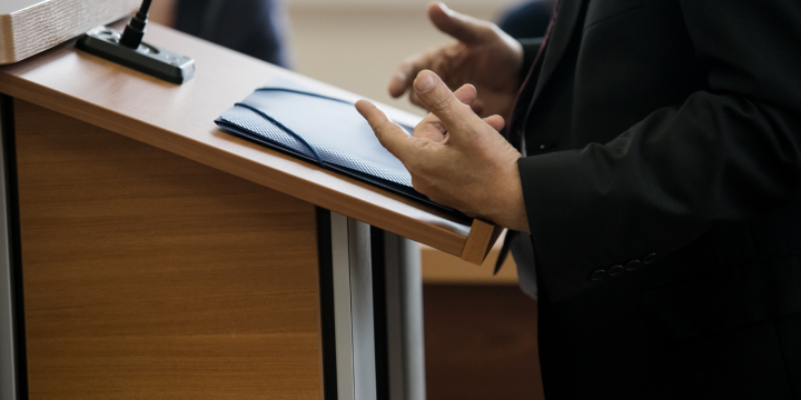 an individual standing at a podium speaking, only their hands and the podium are visable