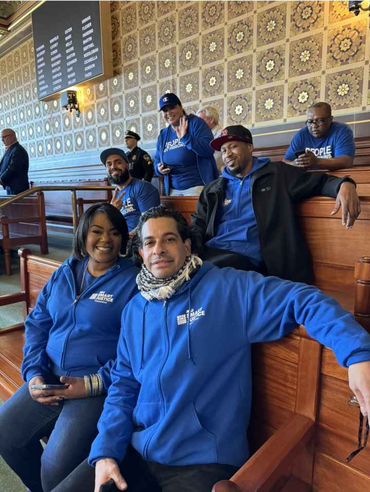 In the Senate room, five of our Smart Justice leaders are sitting together and smiling at the camera with their Smart Justice blue apparel.