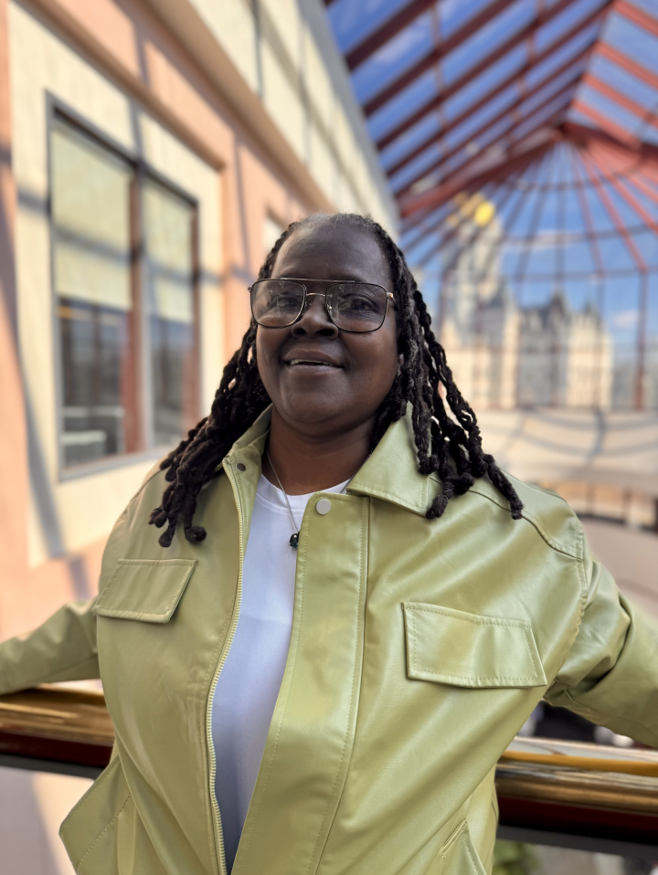 Terri, one of our Smart Justice Leaders, is a Black woman wearing a yellow leather jacket with her hair in a protective style (locs) and black wire rim glasses.