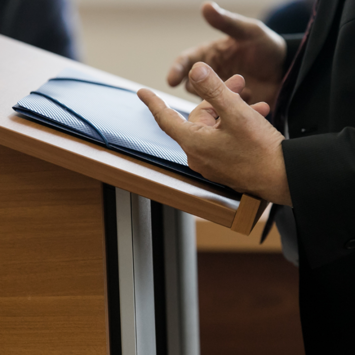 an individual standing at a podium speaking, only their hands and the podium are visable