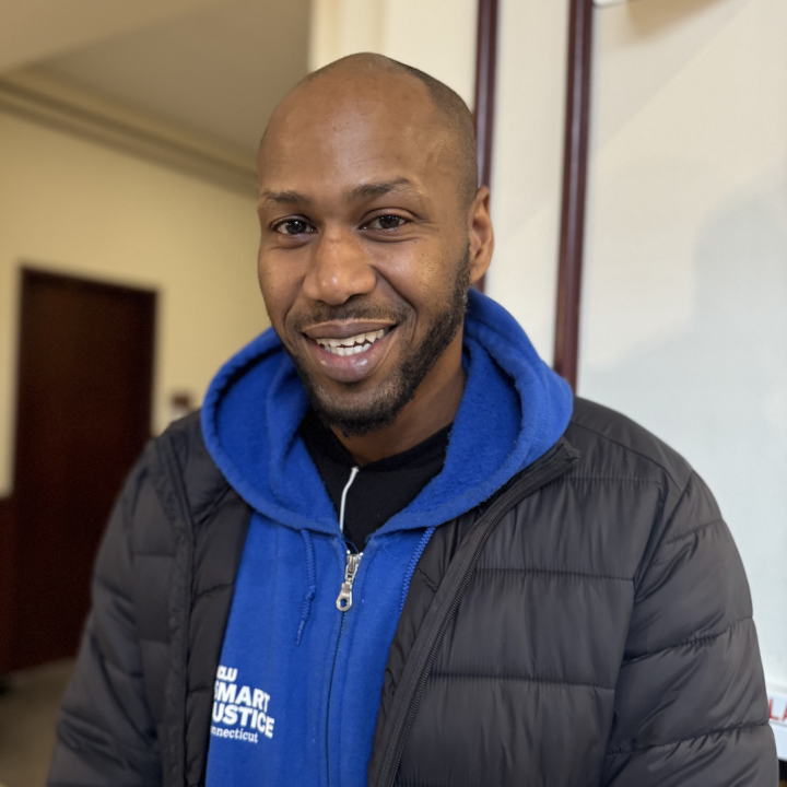 Chris, a Smart Justice Leader, is smiling at the camera wearing one of the smart justice zip ups.