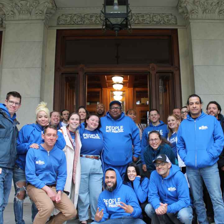 A group of approximately 20 people wearing ACLU bright blue t-shirts smiling at the camera, standing in front of the Capitol building in Hartford, Connecticut.