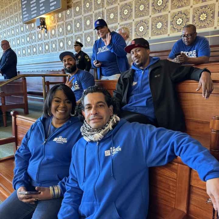 In the Senate room, five of our Smart Justice leaders are sitting together and smiling at the camera with their Smart Justice blue apparel.