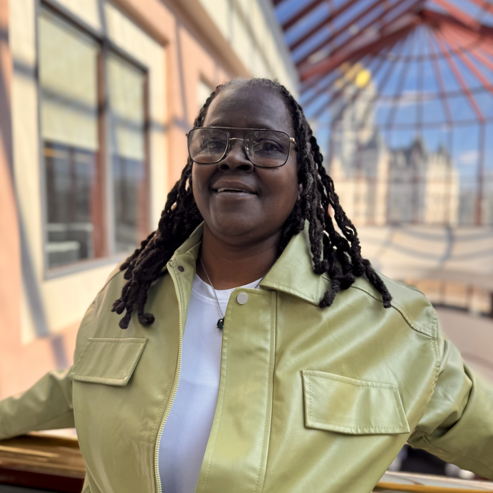 Terri, one of our Smart Justice Leaders, is a Black woman wearing a yellow leather jacket with her hair in a protective style (locs) and black wire rim glasses.