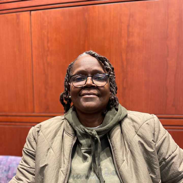 ACLU CT Smart Justice leader Terri Ricks sits, smiling at the camera and wearing a brown jacket and brown hoodie.